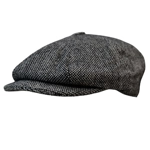 May include: A gray and white tweed newsboy cap. The cap features a rounded crown and a short, stiff brim. The fabric has a textured appearance, with a pattern of small, interwoven threads. This classic style is suitable for various occasions.