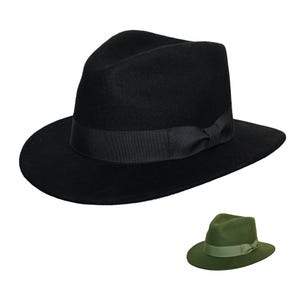 Może przedstawiać: Czarny kapelusz typu fedora z czarną wstążką rypsową i klasyczną koroną w kształcie łzy. Kapelusz ma szerokie rondo i lekko wklęsłą koronę. Widoczny jest również mniejszy, oliwkowozielony fedora.