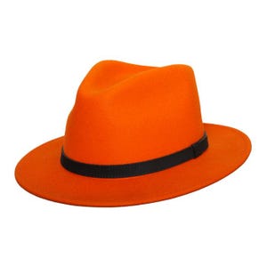 Puede incluir: Sombrero fedora naranja brillante con una banda negra. El sombrero tiene una forma clásica de fedora con una corona plegada y un ala ancha. La banda negra rodea la base de la corona, agregando un detalle de contraste. Un accesorio elegante.