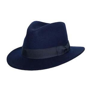 Puede incluir: Un sombrero fedora azul marino con una cinta negra. El sombrero tiene una forma clásica con ala ancha y copa hundida. Un accesorio elegante, adecuado para diversas ocasiones.