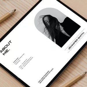 May include: A digital tablet displays a minimalist design with the text "ABOUT ME." and a black and white photo of a person. The name "JENNIFER SMITH" is also visible. Two pencils are on the wooden surface.