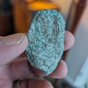 May include: A close-up of a green and gray rock with a rough texture.