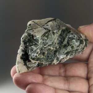 May include: A rough, clear quartz crystal with green inclusions. The crystal is irregularly shaped and has a natural, raw appearance.