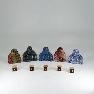 May include: Five small stone laughing Buddha figurines in different colors and patterns. The figurines are arranged in a row from left to right, numbered 1 through 5.