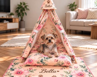 Può includere: Una tenda tipi per animali domestici con motivo floreale rosa, dotata di tappetino abbinato e un piccolo cane all'interno. La tenda e il tappetino sono personalizzati con il nome Bella, un'icona a forma di cuore e impronte di zampe.