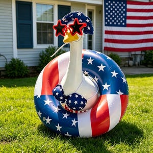 May include: A whimsical goose statue wearing star-shaped sunglasses, a patriotic hat, and a bikini, all in red, white, and blue. The goose is inside a matching inflatable ring, with an American flag in the background.
