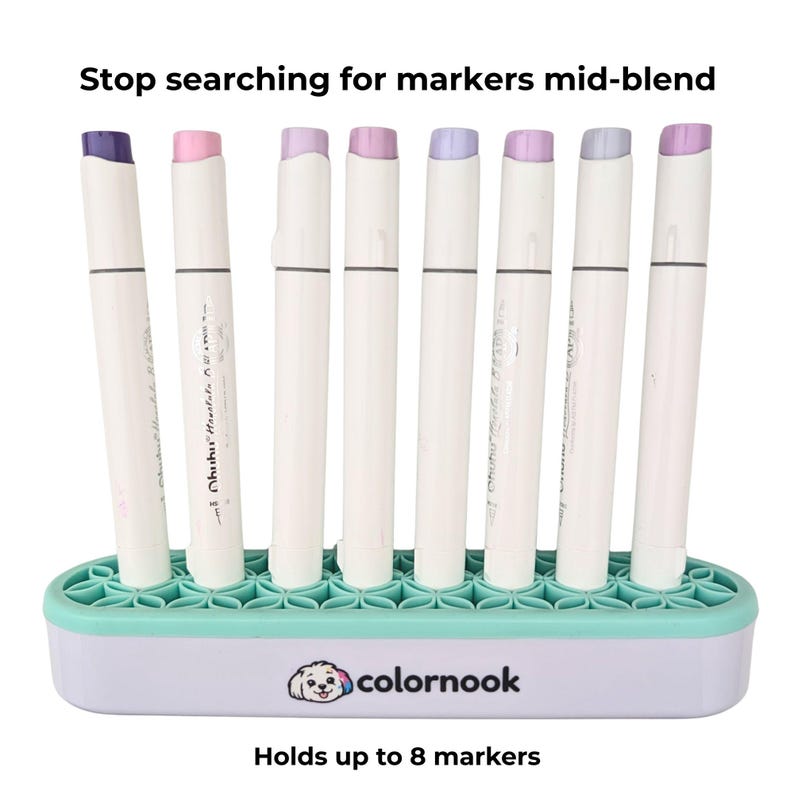 May include: A white marker organizer with a mint green silicone top featuring a floral grid pattern. The base displays the text colornook and a dog icon. Eight markers with white barrels and pastel caps are inserted. Text reads Stop searching for markers mid-blend and Holds up to 8 markers.