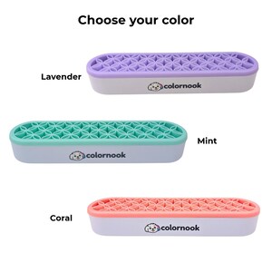 May include: Three elongated oval organizers with white bases and the text colornook featuring a dog logo. Each has a silicone top with a geometric flower pattern in lavender, mint, or coral. The text Choose your color is at the top.