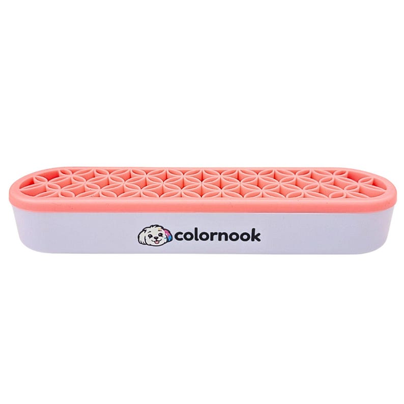 May include: A rectangular white organizer with a coral pink top featuring a repeating geometric flower pattern. The front side displays a small graphic of a dog with a colorful ear and the text colornook in black lowercase letters.