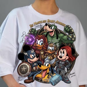 May include: White t-shirt featuring a graphic of Disney characters as Avengers. The design includes Mickey Mouse as Captain America, Minnie Mouse as Black Widow, and Goofy. Text includes "The Marvelous Disney Avengers" and character names.