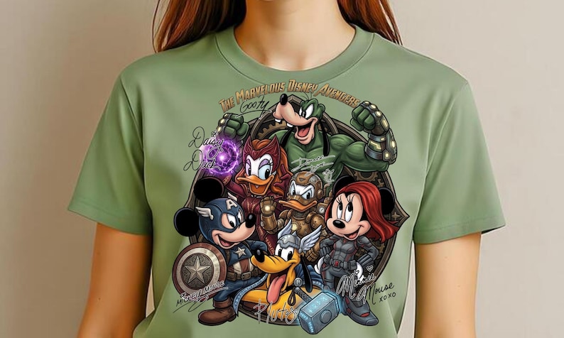 May include: Sage green t-shirt featuring a graphic of Disney characters as Avengers. The design includes Mickey Mouse as Captain America, Minnie Mouse as Black Widow, and Goofy. Text reads "The Marvelous Disney Avengers".