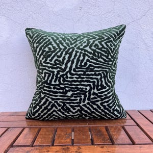 May include: A square throw pillow featuring a dark forest green and black velvet-like fabric with a raised, intricate maze-like geometric pattern. The design consists of interconnected, winding lines that create a dense, textured surface across the front.