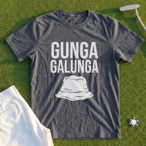 Könnte beinhalten: Ein anthrazitfarbenes Kurzarm-T-Shirt mit dem weißen Schriftzug "GUNGA GALUNGA" über einer grafischen Abbildung eines Fischerhutes. Das T-Shirt hat einen Rundhalsausschnitt und besteht aus einem einfarbigen Stoff in einer Standardpassform.