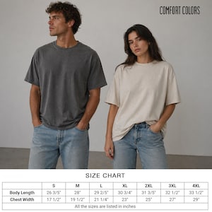 Pode incluir: Duas pessoas vestindo camisetas Comfort Colors e jeans azuis. Uma camisa &eacute; cinza escuro, a outra bege. A imagem inclui uma tabela de tamanhos com medidas em cm para o comprimento do corpo e a largura do peito, do tamanho S ao 4XL.