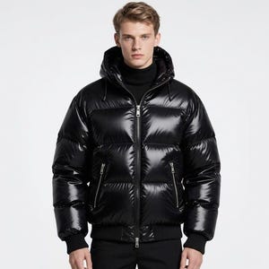 Könnte beinhalten: Eine glänzende schwarze Steppjacke mit Kapuze und Reißverschluss. Die Jacke hat einen gerippten Saum und Bündchen sowie zwei Reißverschlusstaschen. Das Material hat ein glänzendes Finish, das Licht reflektiert. Die Jacke ist für kaltes Wetter konzipiert.