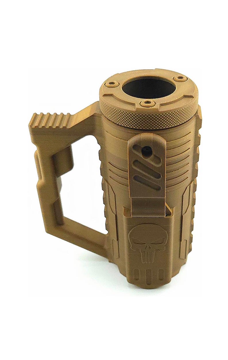 May include: A tan-colored mug with a tactical design. It features a handle, a textured lid, and a skull emblem. The mug has a cylindrical body with vertical ridges and a hinged cover.