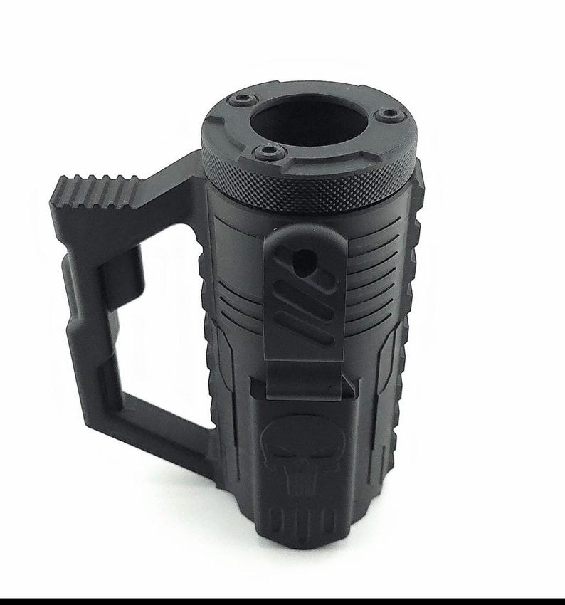 May include: Black tactical-style mug with a textured surface and a large handle. The mug features a skull design and a unique top with multiple holes. The mug is made of a durable material and is designed for rugged use.