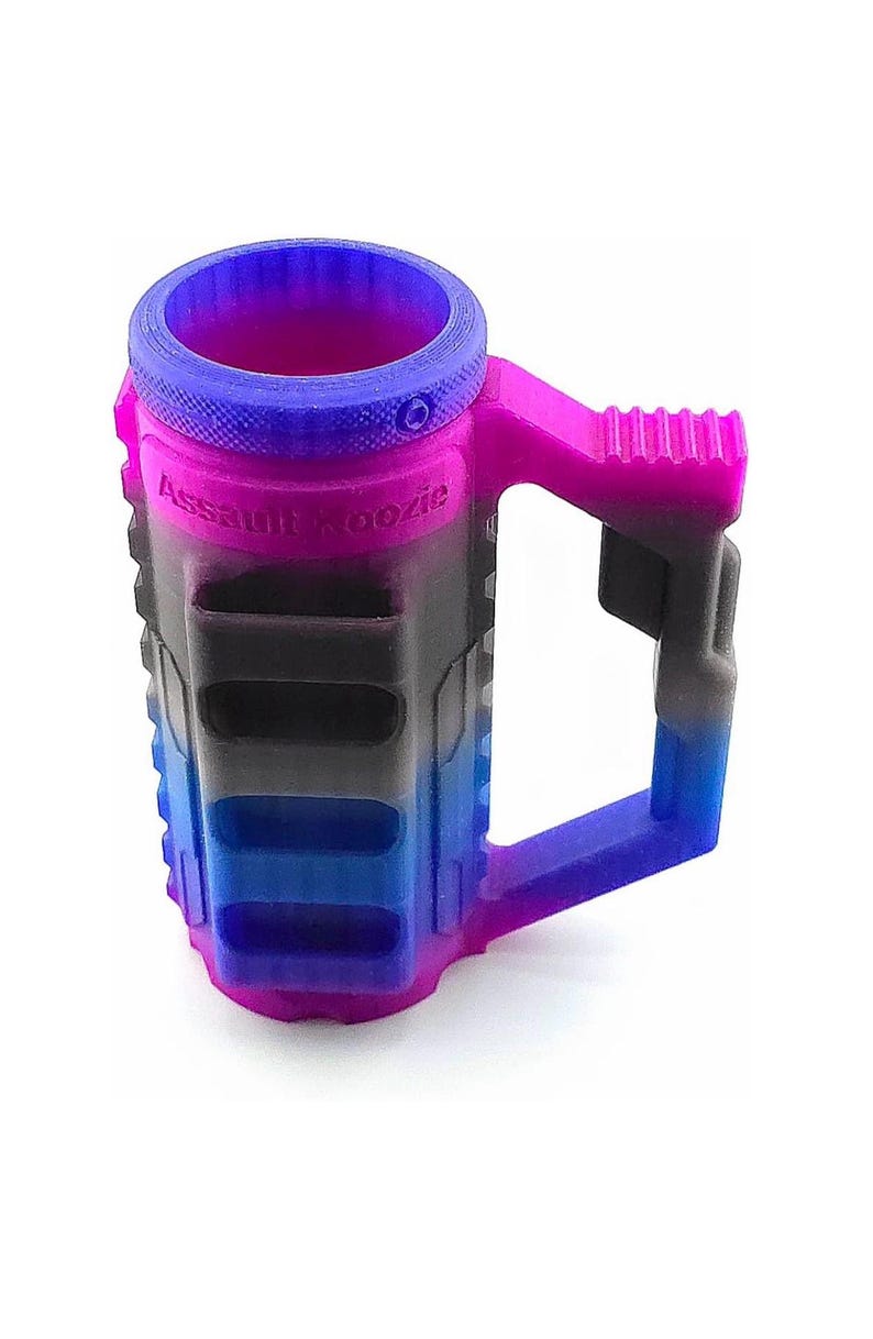 May include: A multi-colored drink koozie with a handle. The koozie is primarily pink, blue, and black, with the text "Assault Koozie" printed on the side. The handle and rim are a gradient of pink and blue.