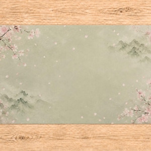 May include: Rectangular placemat with a soft green background, featuring a watercolor design of pink cherry blossoms and misty mountains. The design is reminiscent of traditional Asian art, with a delicate and serene aesthetic.