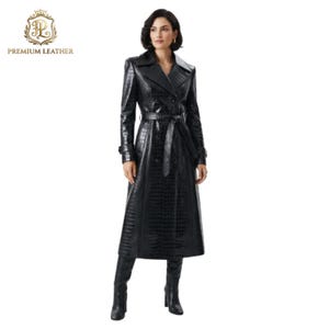 Peut inclure: Un trench-coat noir à manches longues avec une texture gaufrée façon crocodile, un large col cranté, une fermeture à double boutonnage et une ceinture à nouer assortie à la taille. Le manteau descend jusqu'au milieu du mollet et est porté avec des bottes noires.