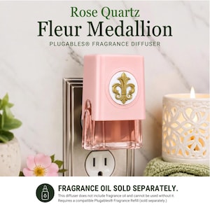 May include: A light pink Plugables fragrance diffuser featuring a gold fleur-de-lis medallion on a white circular background. The device is plugged into a wall outlet and includes a clear, light pink liquid reservoir at the base of the unit.