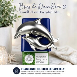 May include: A blue Belle Aroma Plugables fragrance diffuser featuring a silver-toned metallic dolphin pair. The base is green with white text reading Plugables Fragrance Diffuser. The top text reads Bring the Ocean Home Coastal Charm. Everyday Calm.