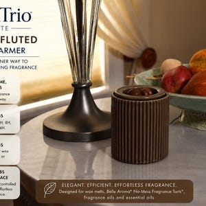 May include: A cylindrical mocha-colored wax warmer with a vertical fluted texture. Text on the image reads: ScentTrio Petite Mocha Fluted Wax Warmer, No Flame No Fuss, 4 Timer Settings, 3 Heat Settings, No Bulbs To Replace, Elegant Efficient Effortless Fragrance.