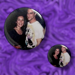 May include: Two circular images of a couple, set against a swirling purple background. The larger image shows a smiling woman in a black top and a man in a white graphic t-shirt. A smaller version of the same image is also present.