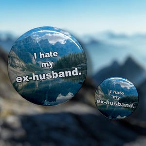 May include: Two round buttons with a scenic mountain and lake background. The text "I hate my ex-husband" is printed on the buttons. The buttons are glossy and have a slight dome shape.