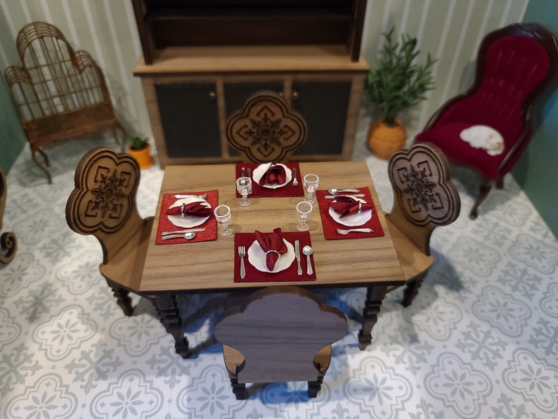 May include: A wooden dining table set with four chairs, red placemats, white plates, and silverware. The table is set for a formal dinner.
