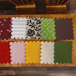 Puede incluir: Ocho cuadrados de tela festoneados en varios colores y patrones, incluyendo rojo, blanco, marr&oacute;n, verde, amarillo e impresiones florales. Los cuadrados est&aacute;n dispuestos en dos filas de cuatro sobre una superficie de madera.