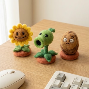 May include: Three felted figures from the Plants vs. Zombies game. A smiling sunflower, a peashooter, and a walnut are displayed on a wooden surface. Each figure is on a small orange base. A computer mouse and keyboard are in the foreground.