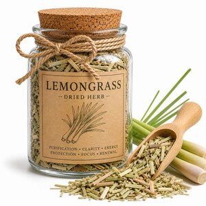 May include: A glass jar filled with dried lemongrass, labeled "LEMONGRASS - DRIED HERB." A wooden scoop holds more dried lemongrass, with fresh stalks alongside. The label also lists "PURIFICATION • CLARITY • ENERGY • PROTECTION • FOCUS • RENEWAL."