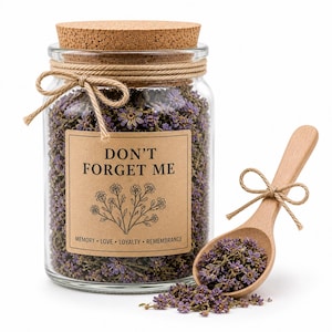 Puede incluir: Un tarro de cristal transparente lleno de flores moradas secas, sellado con una tapa de corcho y cuerda. Una cuchara de madera contiene más flores. El tarro tiene una etiqueta que dice "DON'T FORGET ME" con las palabras "MEMORY • LOVE • LOYALTY • REMEMBRANCE".