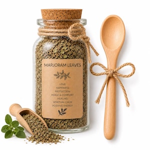 May include: A glass jar filled with dried marjoram leaves, a wooden spoon, and a small wooden scoop. The jar has a cork stopper and a label that reads "Marjoram Leaves" with additional text. The spoon and jar are tied with twine.