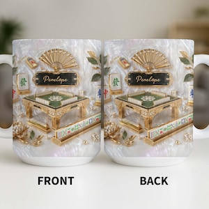 May include: White ceramic mug featuring a detailed design of a Mahjong table, fan, and tiles. The mug has a pearlescent background and the name "Penelope" on a plaque. The front and back of the mug are visible.