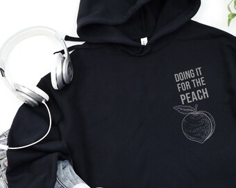 May include: Black cropped hoodie with a white graphic of a peach and the text "Doing it for the Peach".