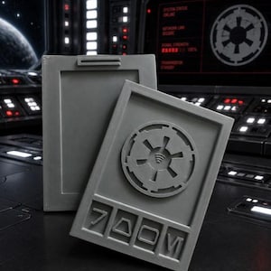 May include: Two rectangular gray plastic data pads with a matte finish. The front pad features a circular Imperial crest emblem at the top and four distinct geometric symbols embossed in a row at the bottom. The back pad is plain with a top clip.