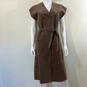 May include: A brown suede dress with a V-neckline, short sleeves, and a button-up front. The dress has a belt and a midi length.
