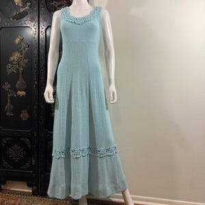 May include: A light blue maxi dress with a crocheted lace trim around the neckline and hem. The dress has a sleeveless design and a fitted bodice.