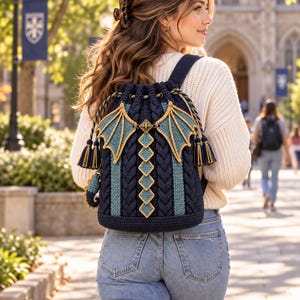 May include: A dark navy blue crochet drawstring backpack featuring a central vertical row of diamond-shaped accents, two decorative dragon-like wings on the sides, and braided straps. The bag includes gold-toned hardware and matching tassels.