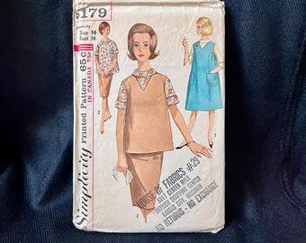 May include: Vintage Simplicity printed sewing pattern. The pattern features illustrations of a woman wearing a skirt suit, a dress, and a top with floral accents. The pattern is for a size 14 with a bust of 34 inches.