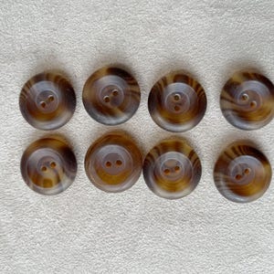 May include: Eight brown and black swirl patterned buttons with two holes each.
