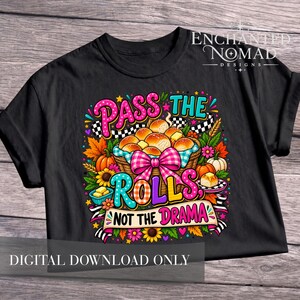 Può includere: Una t-shirt nera con una grafica colorata di un cestino di panini con un fiocco a quadretti rosa. Il testo "PASS THE ROLLS, NOT THE DRAMA" è scritto in lettere vivaci e audaci, circondato da foglie autunnali, girasoli e zucche.