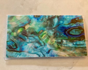 May include: A clear plastic wallet with a blue, green, and gold iridescent pattern.