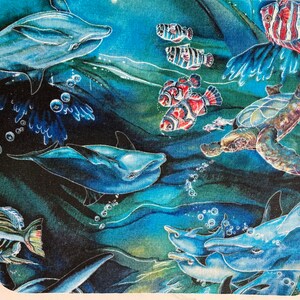 Puede incluir: Una escena submarina colorida con delfines, una tortuga marina y peces tropicales. El fondo es una acuarela azul y verde.