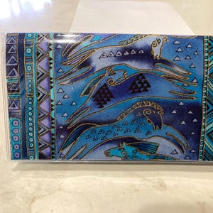 Op de afbeelding: Een rechthoekige etui met een blauw stoffen ontwerp met gestileerde paarden in tinten blauw en goud. De etui heeft een doorzichtige plastic hoes en een decoratieve rand met geometrische patronen in blauw, paars en goud.