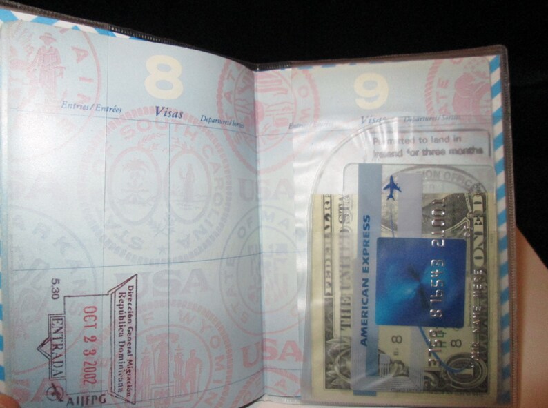 May include: A passport with a blue and white American Express card and a US dollar bill inside a clear plastic pocket. The passport has a stamp from the Dominican Republic dated October 23, 2002.