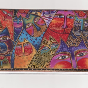 May include: A vibrant, artistic design showcasing multiple stylised cat faces. The cats display diverse patterns and colours, such as red, blue, orange, and purple, with gold detailing. The overall theme is playful and decorative.