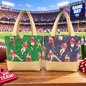 May include: Two tote bags with beige handles and bases. One bag features a green background, the other a dark blue background. Both display a repeating pattern of football players in red jerseys and white pants, along with white play diagrams.